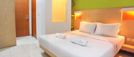 A hotel room with a large bed, two bedside lamps, and a green accent wall.