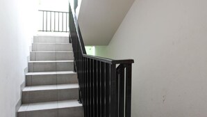 Un escalier avec une rampe noire, menant à l’étage supérieur.