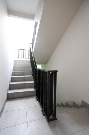 Stairs lead upwards in a spacious interior with a black handrail and light-colored steps.