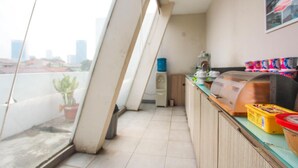 Un balcon avec vue sur la ville, un petit coin cuisine équipé d’un barbecue et une plante en pot.