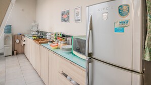 Une cuisine équipée d’un réfrigérateur, d’un four à micro-ondes et de divers ustensiles de cuisine disposés sur le plan de travail.