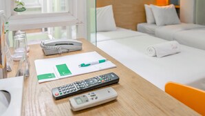 Une chambre d’hôtel avec un bureau en bois, un lit avec une literie blanche, une lampe de chevet et une fenêtre donnant sur l’extérieur.