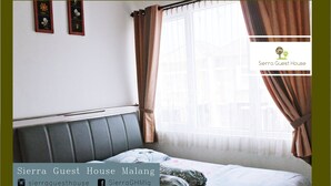A bedroom with a bed, curtains, and a window. - Sierra Villa Malang (Malang)