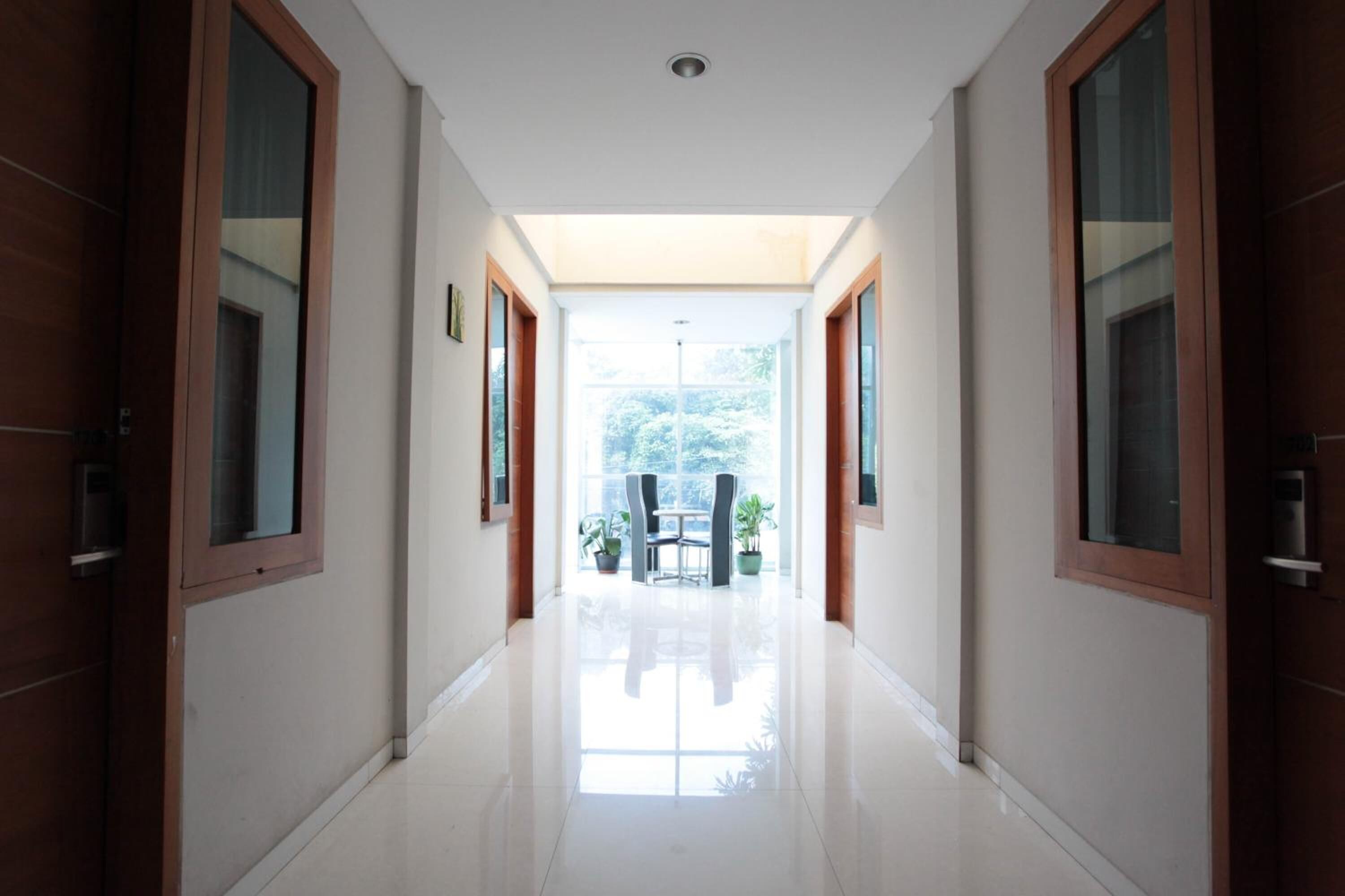 A hallway with a view to a patio area, featuring a table and chairs, and a door on the left.