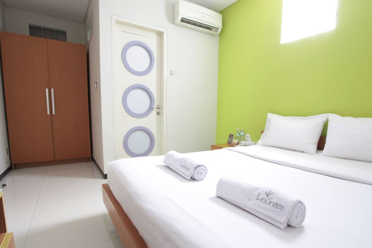 Habitación de hotel con cama, armario y baño con espejo e inodoro.