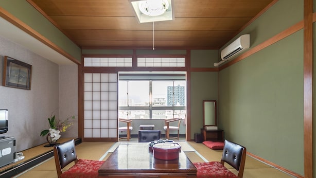 Ett traditionellt japanskt rum med tatamimattor på golvet, ett träbord och låga sittplatser.