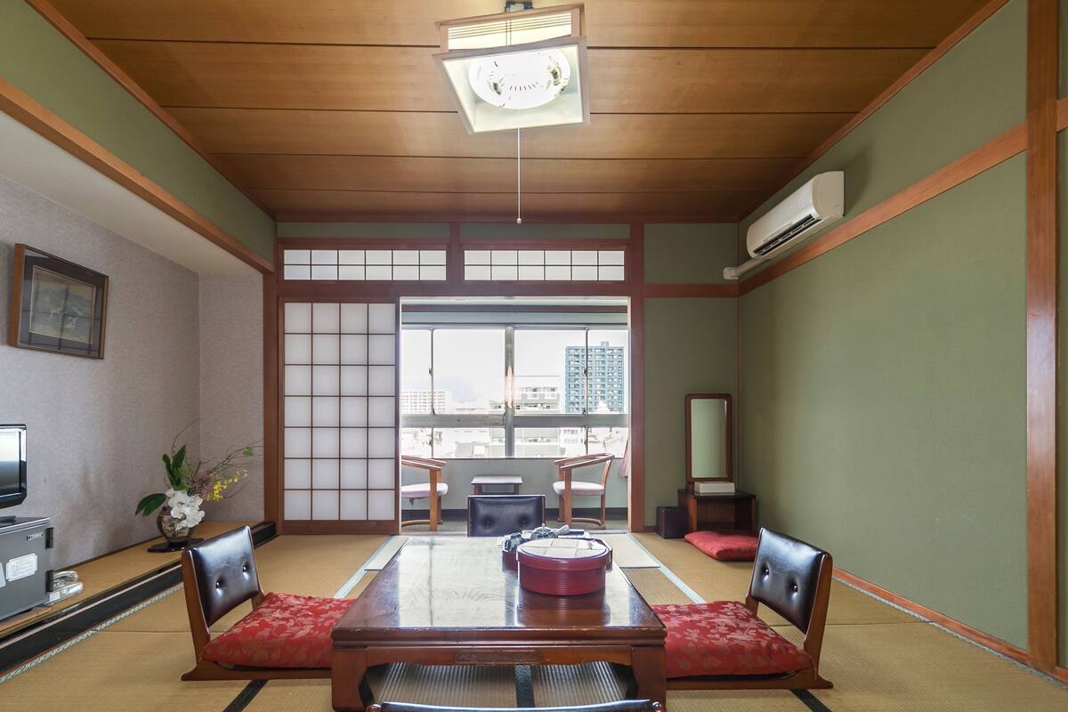 Um quarto japonês tradicional com tatames, uma mesa de madeira e assentos baixos.