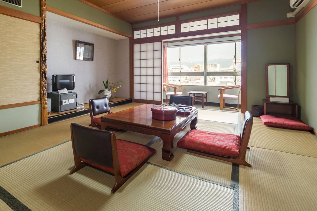 Quarto japonês tradicional com tatames, uma mesa baixa e cadeiras de madeira.