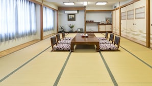 Ett traditionellt japanskt rum med tatamimattor på golvet, ett träbord och stolar med mönstrade kuddar.