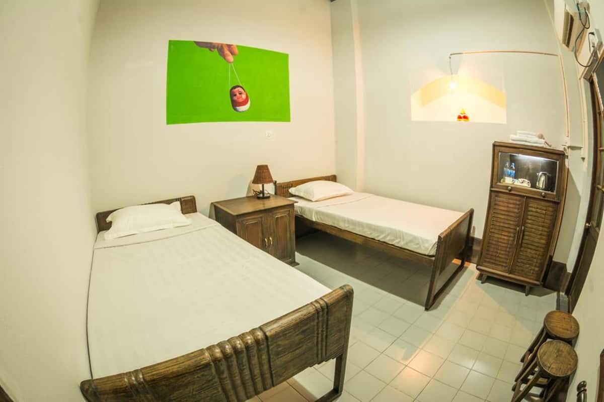 A room with two single beds, a wooden cabinet, a small table, and a wall-mounted television.