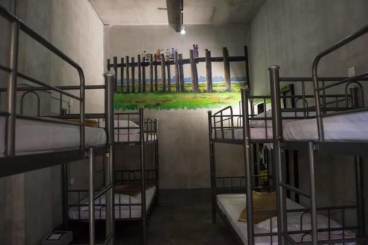A dormitory room with bunk beds, a mural on the wall, and a ceiling light.