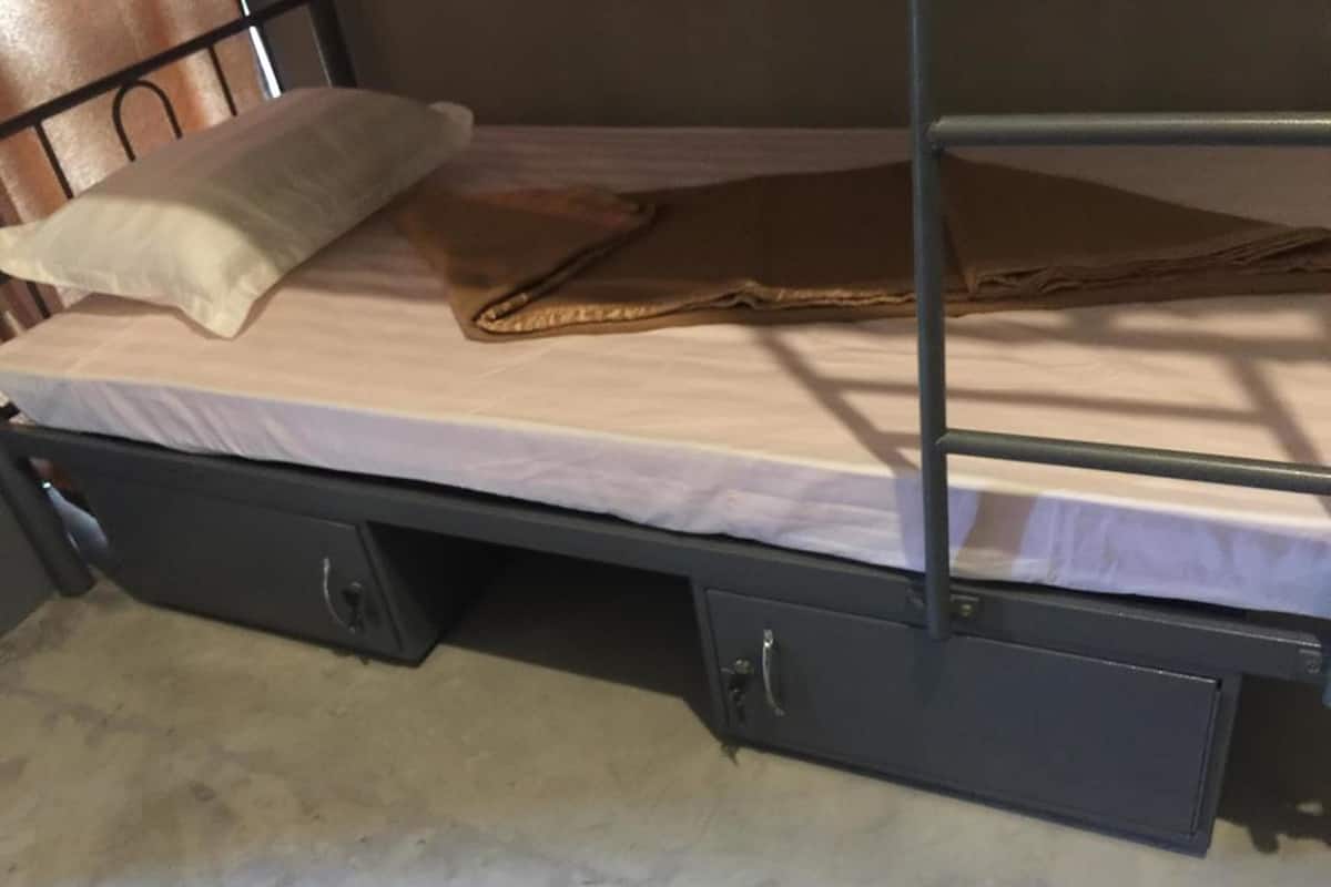 A bunk bed with a mattress, pillows, and a folded blanket. There are two drawers under the bed.