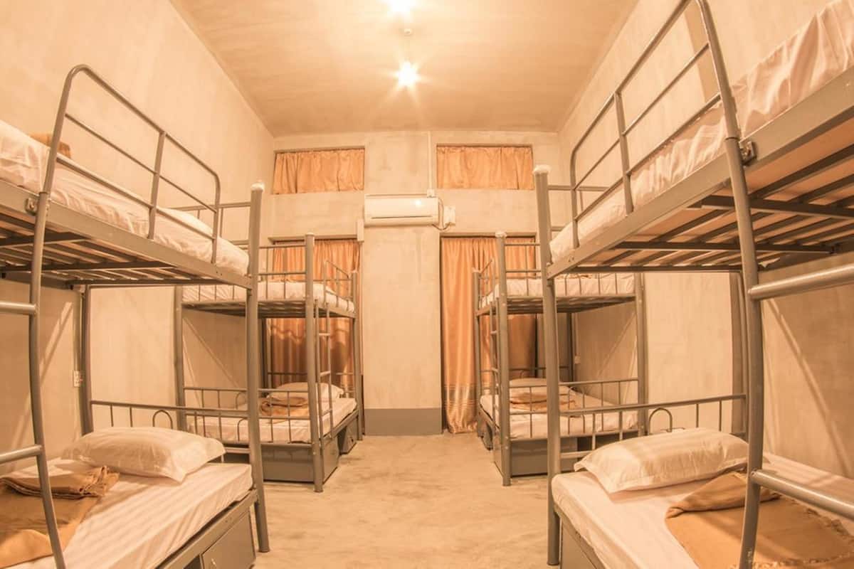 A dormitory room with bunk beds, an air conditioning unit, and curtains.