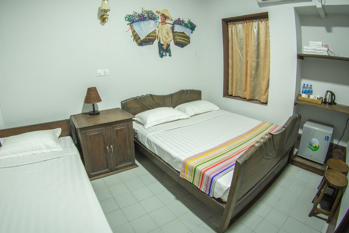 A bedroom with a bed, a nightstand, a lamp, a wardrobe, a shelf with toiletries, and a wall decoration.