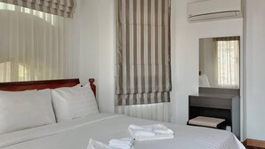 A hotel room with a large bed, a wooden headboard, a bedside table with a mirror, and an air conditioning unit on the wall. - Rumnea Apartment (Phnom Penh)