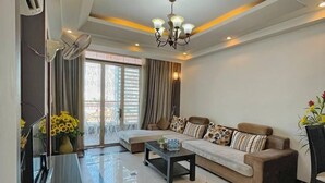 A modern living room with a sofa, coffee table, and a chandelier. - Rumnea Apartment (Phnom Penh)