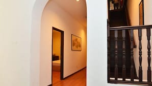 A hallway with a wooden floor, a staircase with a black balustrade, and a framed picture on the wall. - Cheng Ho Residence (Malacca City)