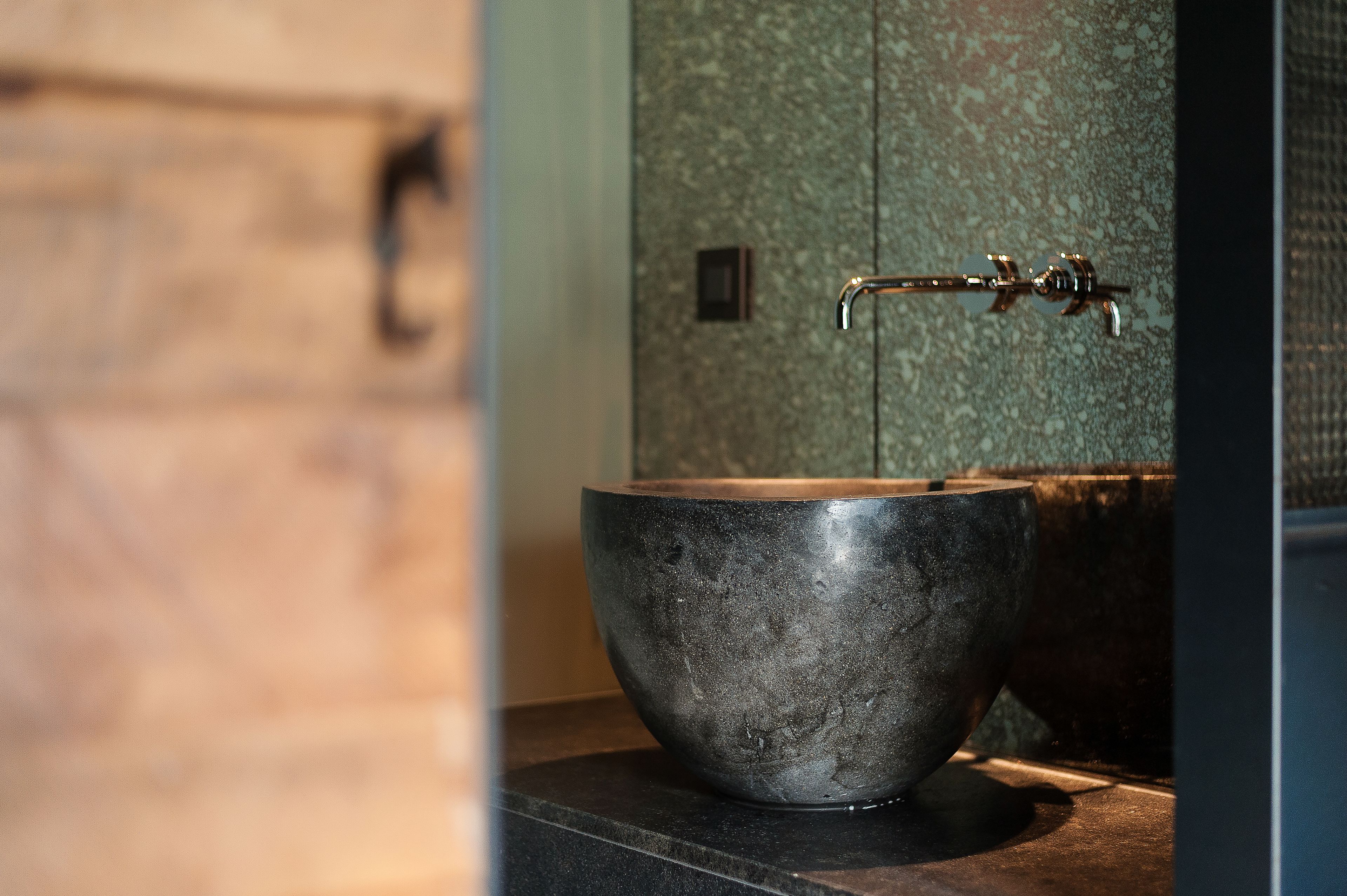A modern bathroom with a large, dark stone basin and a sleek faucet.