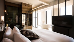 A modern hotel room with a large bed, a flat-screen TV, a bathtub, and a walk-in closet. - Hotel Museo (Cheongju)