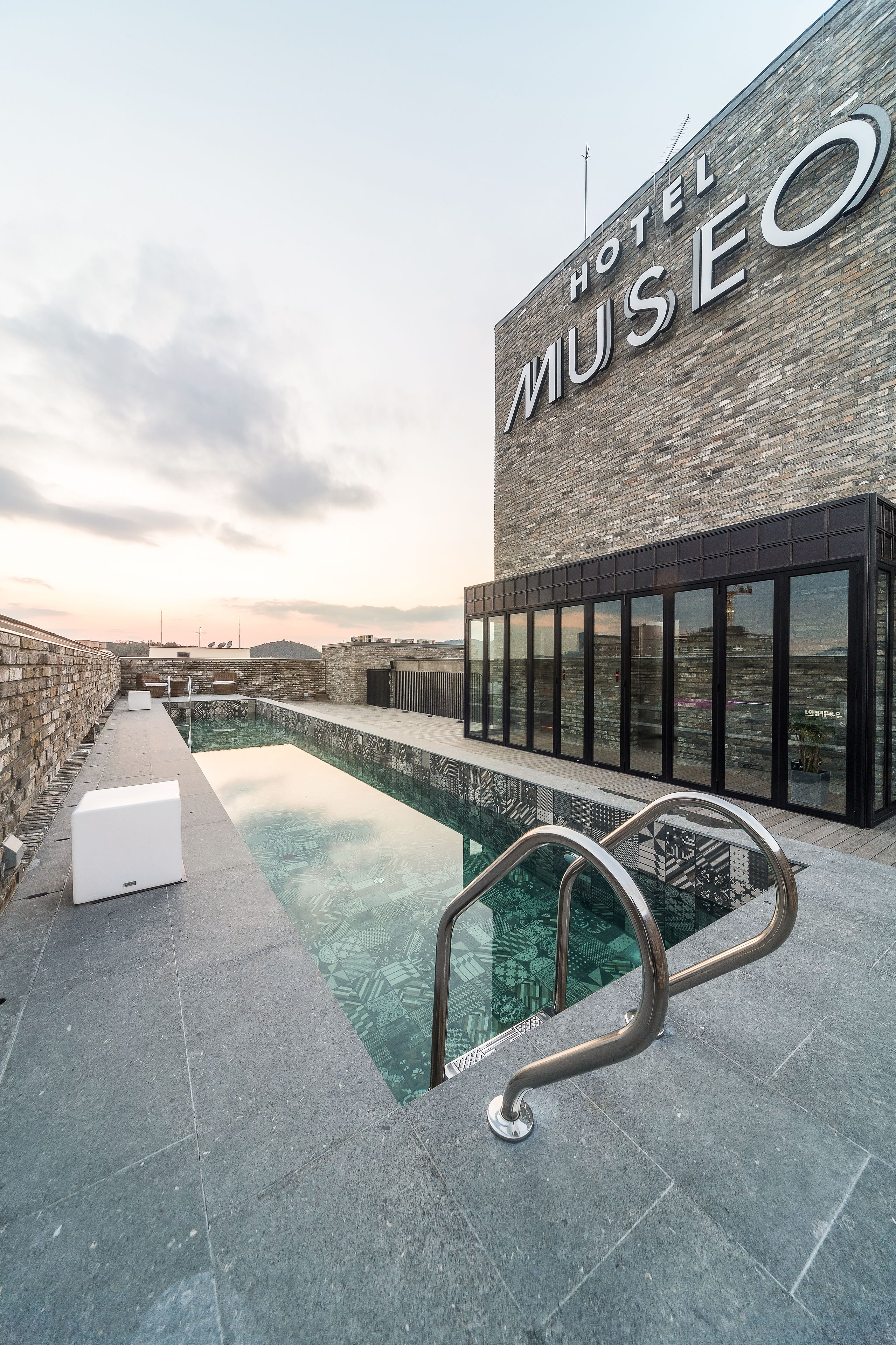 Un hotel con piscina, fachada de ladrillo y un cartel que dice "HOTEL MUSEO".