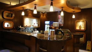 Zona de bar con mostrador, varias lámparas colgantes y dispensador de bebidas.