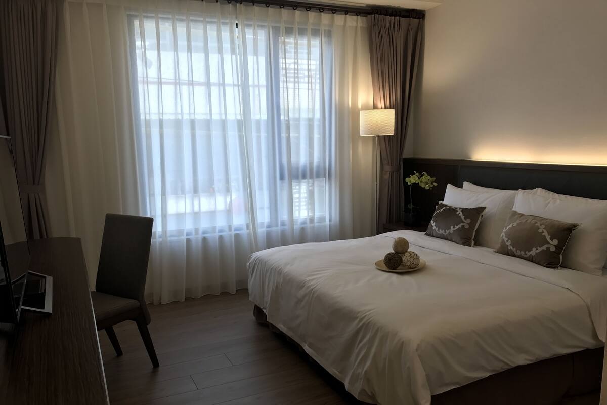 A hotel room with a large bed, a desk, and a chair.