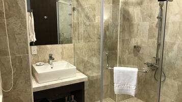 A modern bathroom with a glass-enclosed shower, a white sink, and a dark vanity.