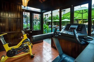 Quarto com bicicleta ergométrica, painel de controle e janelas amplas com guarda-sóis externos.