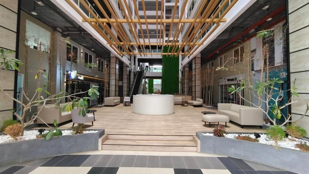 A modern lobby with a central seating area, a staircase, and a green wall.