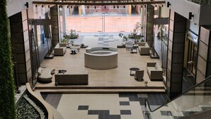 En rummelig lobby med et centralt siddeområde, flisegulv og udsigt til gaden.