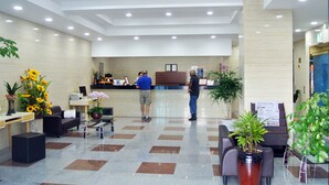 Una moderna zona de recepción con mostrador de entrada, asientos y plantas en macetas.