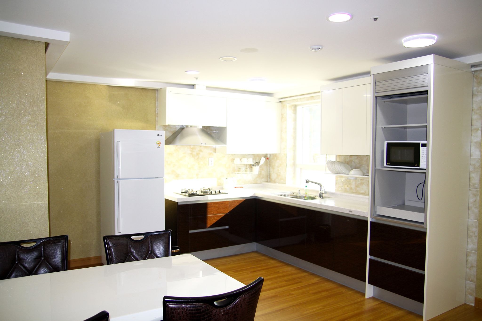 Una cocina moderna con armarios blancos, un microondas integrado y un comedor con mesa y sillas blancas.