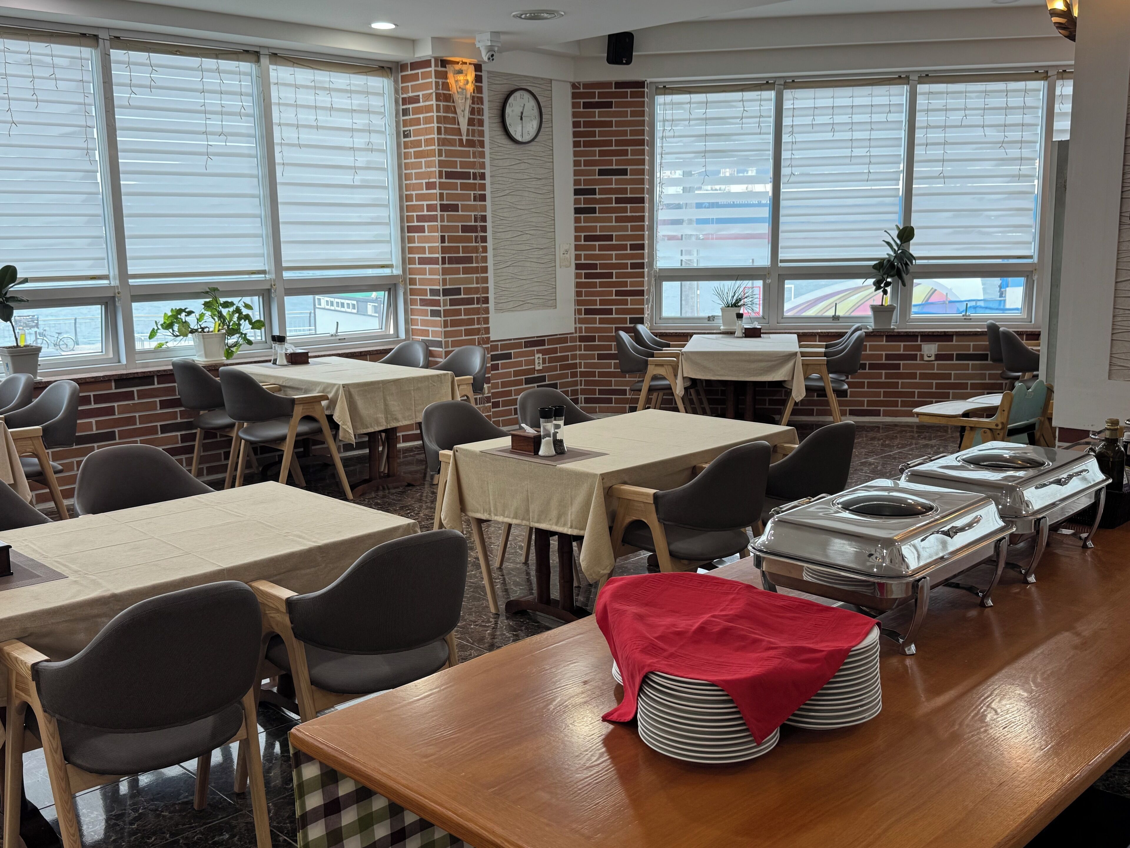 Ein Restaurant mit Ziegelwänden, großen Fenstern und mehreren Tischen und Stühlen.