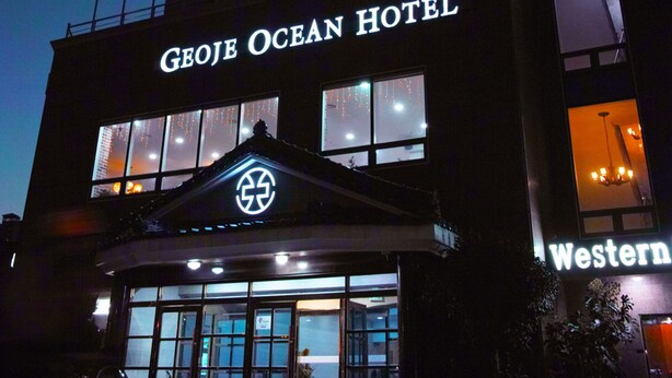 Exterior del Hotel Geoje Ocean, con señalización iluminada y fachada moderna.