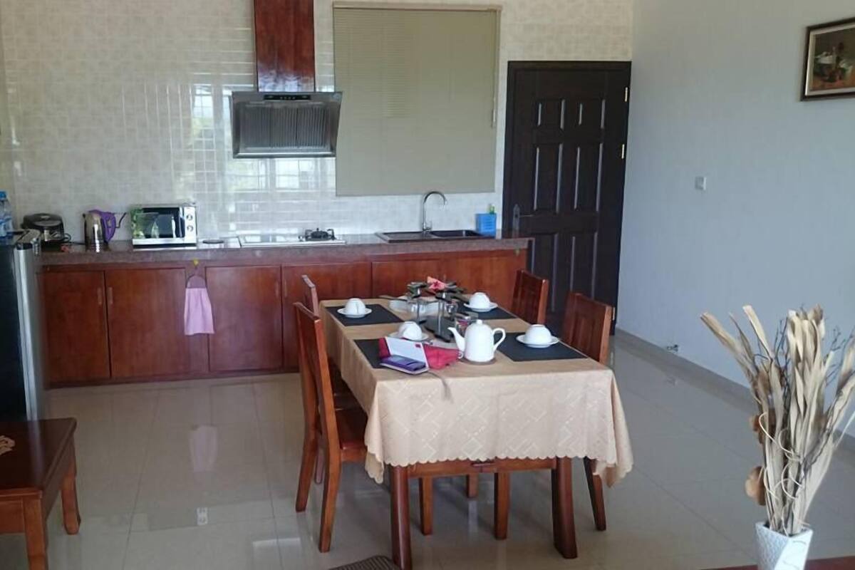 Una cocina con una mesa de comedor para cuatro personas, un microondas y una estufa.