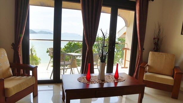 Une pièce avec vue sur la mer, une table ornée de vases rouges et deux chaises.