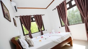 Une chambre à coucher avec un lit en bois, du linge de lit blanc et des rideaux bruns.