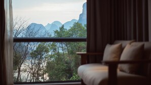 A room with a view of mountains and trees through a window. - Li River Resort (Guilin)