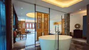 A spacious bathroom with a large bathtub, a wooden cabinet, and a glass partition. - Li River Resort (Guilin)