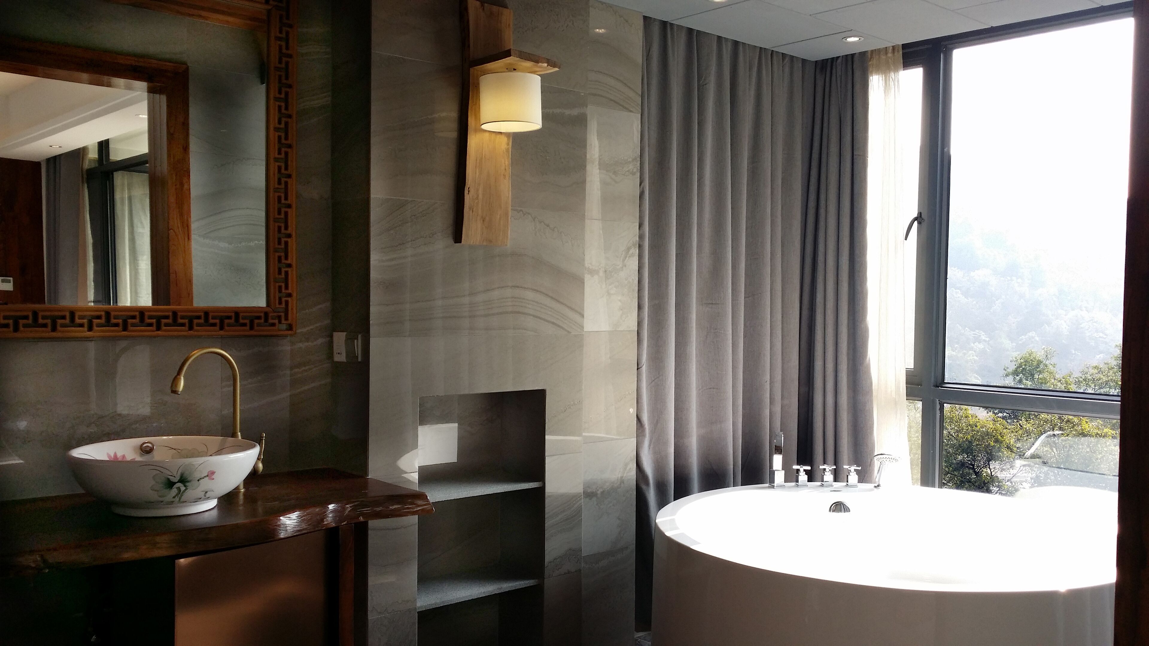 A modern bathroom with a freestanding bathtub, a large mirror, and a vanity with a bowl sink.