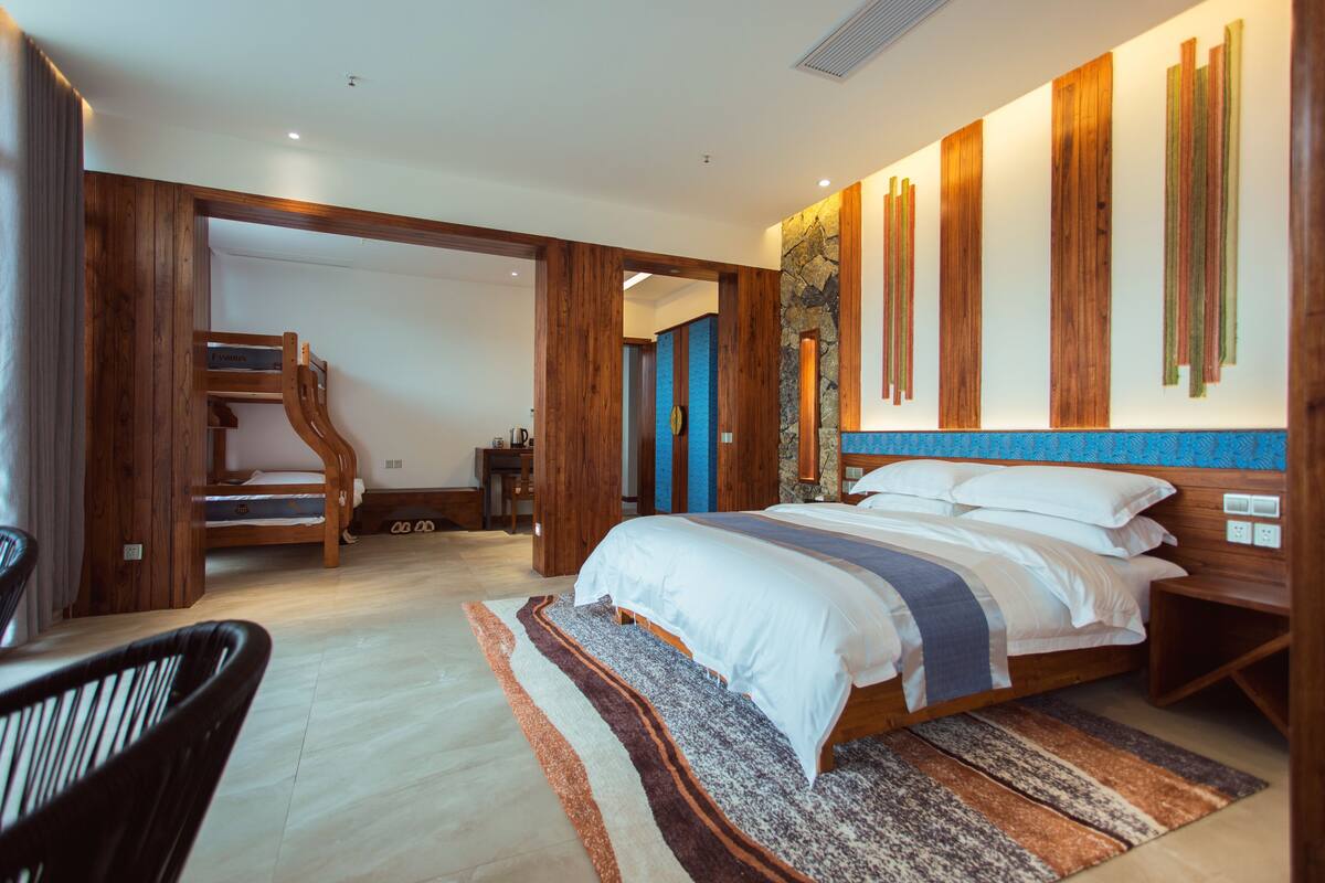 A modern bedroom with a large bed, wooden accents, a blue accent wall, and a staircase leading to another room.