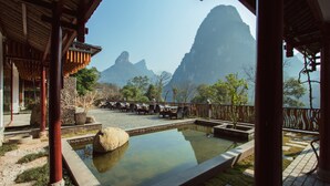 A traditional wooden building with a pool, outdoor seating, and a view of mountains.