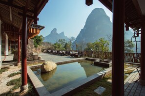 A traditional wooden building with a pool, outdoor seating, and a view of mountains.