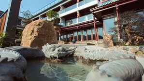 A traditional building with a large rock and a decorative pond in front.