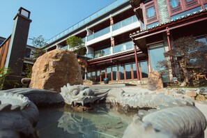 A traditional building with a large rock and a decorative pond in front.