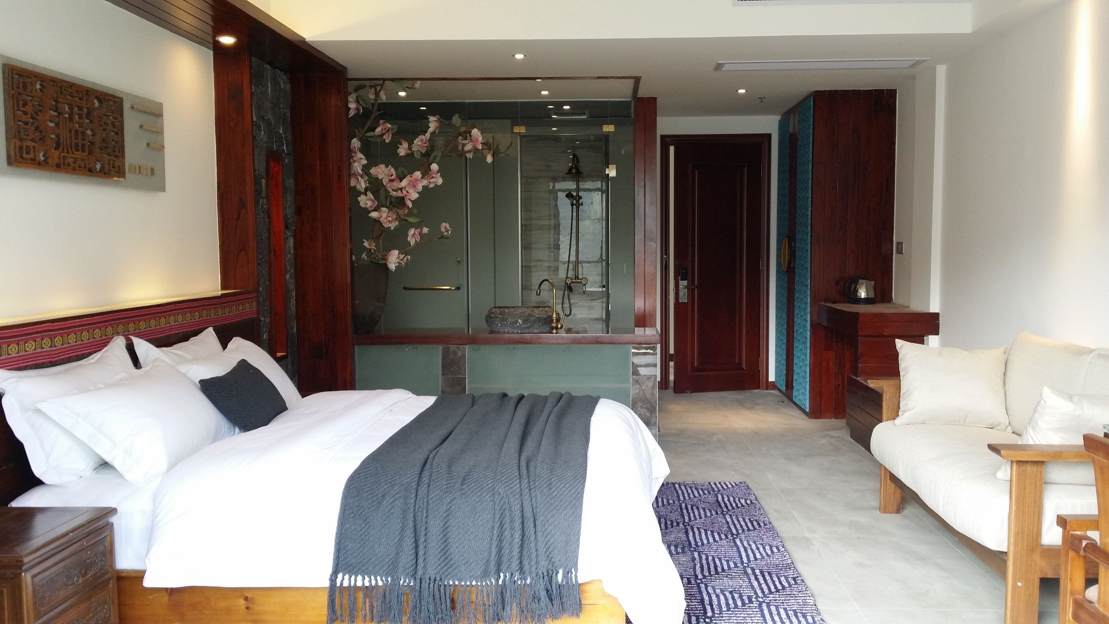 Ein Hotelzimmer mit Bett, Sitzecke, Badezimmer mit Dusche und Spiegel.