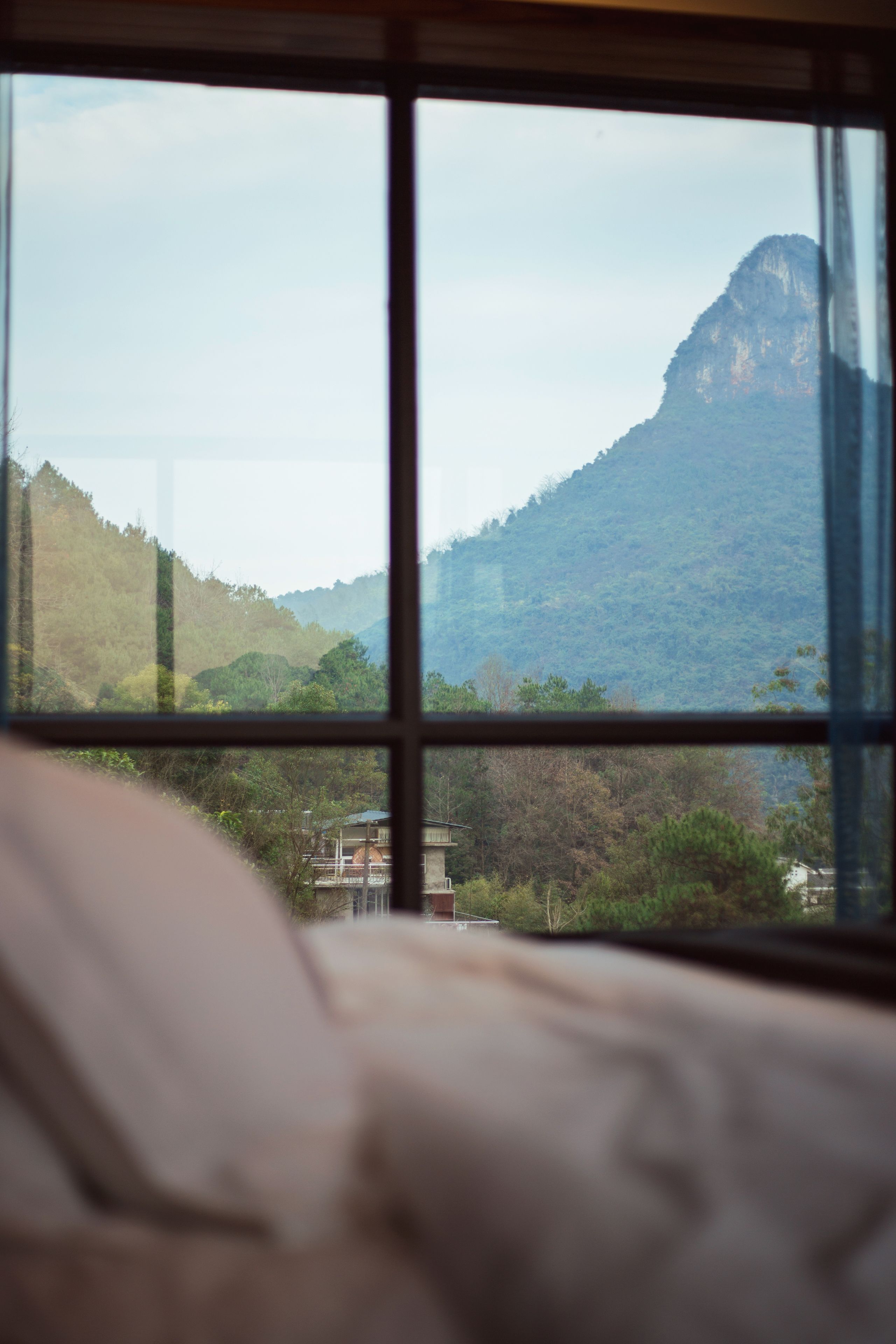A room with a large window overlooking a mountainous landscape.