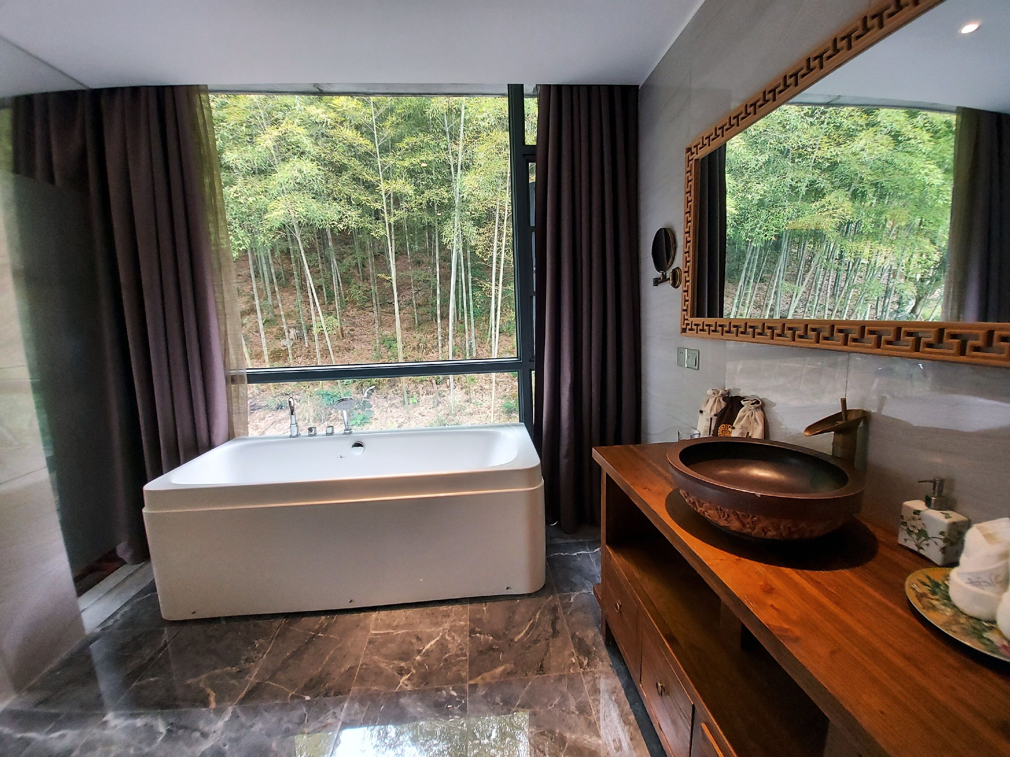 Ein modernes Badezimmer mit einer großen Badewanne, einem Holzbadezimmer-Möbel und einem großen Spiegel.