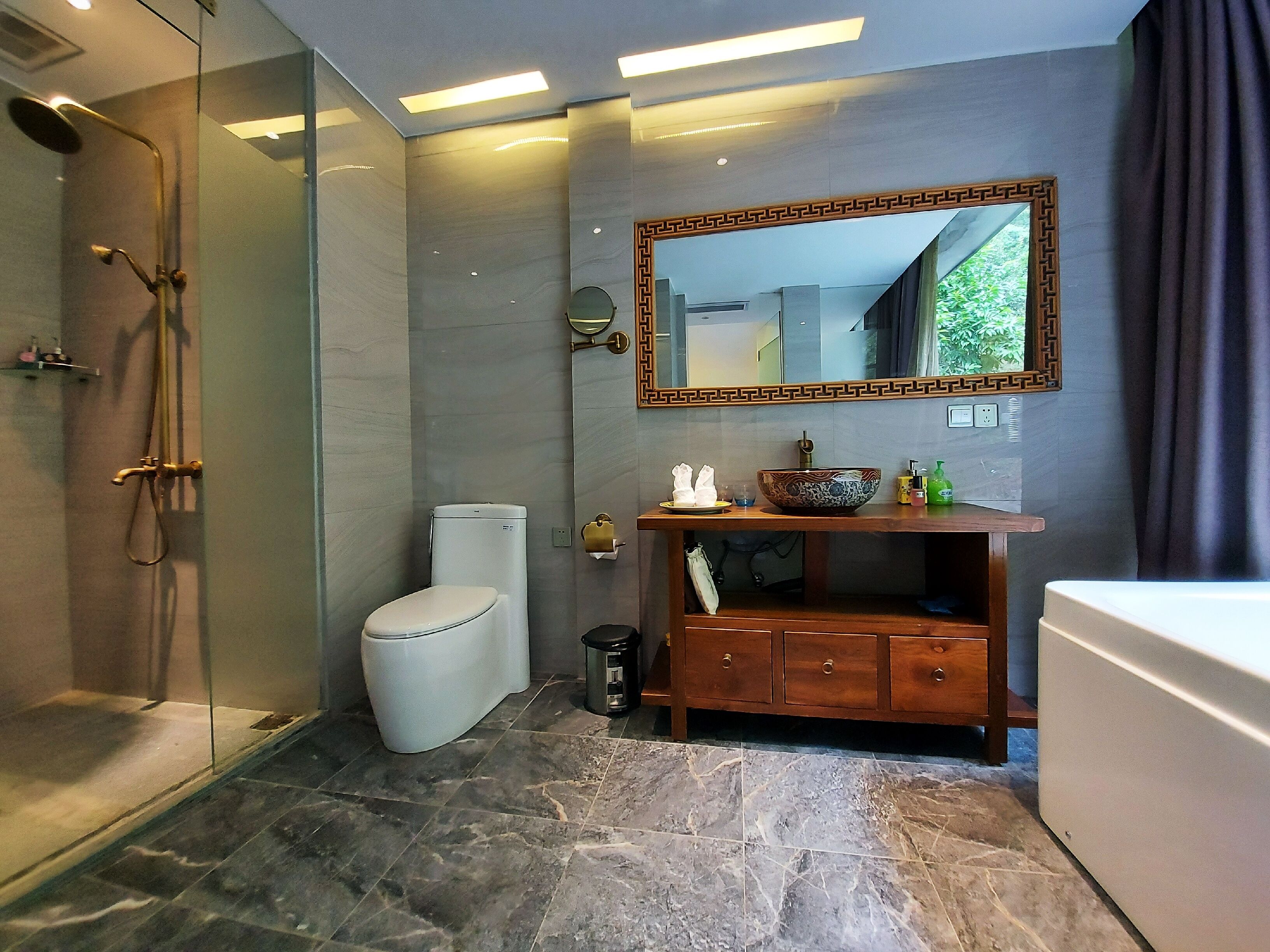 A modern bathroom with a glass-enclosed shower, a toilet, a vanity with a mirror, and a bathtub.
