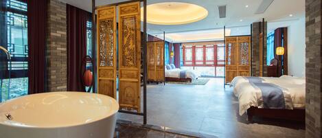 A modern hotel room with a large bathtub, two beds, and traditional wooden decor.